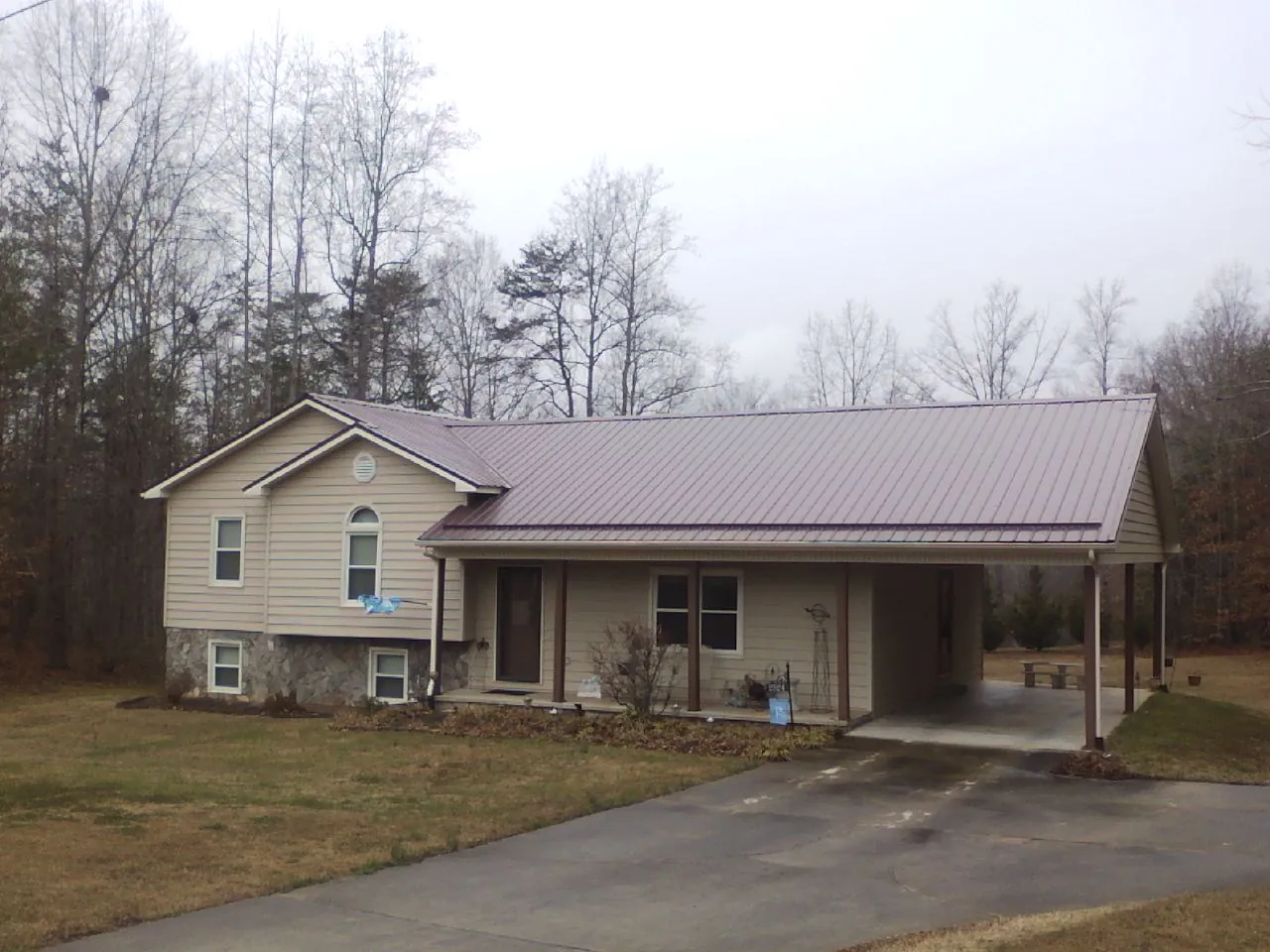 Burgundy metal roof on a tan split level home with an attached carport in Bancroft