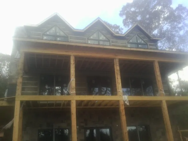 Dormers and porch framing on a large log home under construction — Roof Coating work by our crew in Bancroft